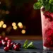 Tall Cranberry Mojito With Ruby-Red Cranberry Sauce Streaks, Fresh Mint, Lime Wedge, And Ice In A Highball Glass