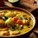 Bowl Of Thick Orange Haitian Pumpkin Soup With Plantain, Carrots, Potatoes, And Fresh Parsley In Earthenware Bowl