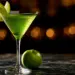 Vivid Green Appletini In A V-Shaped Martini Glass Garnished With Granny Smith Apple Slices On Dark Marble