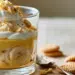 Layered Banana Cream Pudding In A Clear Glass With Custard, Banana Slices, Whipped Cream, And Crushed Wafers