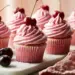 Pink-Swirled Buttercream Cupcakes Topped With Fresh Black Cherries On A White Marble Board