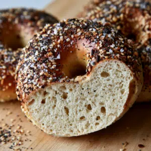 Simple Everything Bagel Recipe - Thefoodiebunch Golden Everything Bagels With Sesame Poppy Seeds And Coarse Salt On A Black Wire Cooling Rack